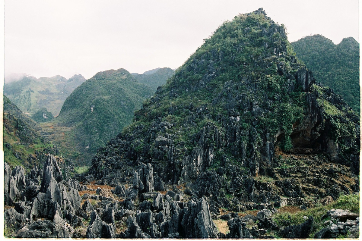 Panoramic view of Dong Van Karst Plateau with towering limestone peaks, winding roads, and scattered ethnic villages in Ha Giang, Vietnam.